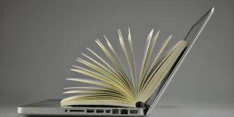 Aufgeklaptter Laptop mit auffächertem Buch