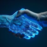 Eine menschliche Hand schüttelt eine künstliche, digital dargestellte Hand. Die digitale Hand besteht aus leuchtenden, blauen Linien und Punkten, die an ein Netzwerk oder ein Schaltkreisdiagramm erinnern. Die Szene ist dunkel gehalten, der Fokus liegt auf dem Handschlag und dem Kontrast zwischen organischer und digitaler Struktur.